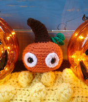 pumpkin plush toy - crocheted amigurumi pumpkin with glass jack o'lanterns against blue wooden background