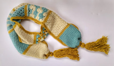 Crochet scarf pattern - scarf shown is ivory, blue and gold with tassels against a white background
